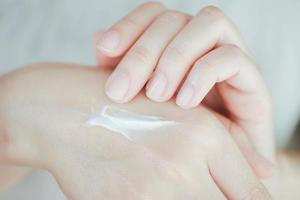crema para la piel en la mano de la mujer para agregar humedad a la piel. concepto de cuidado de la salud de la mano. foto