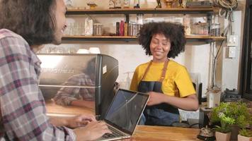 deux partenaires et amis de démarrage d'entreprise de café, une femme afro-américaine et des baristas thaïlandais discutent et sourient joyeusement ensemble au comptoir du café, un emploi de service heureux et un entrepreneur de PME. video