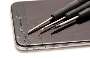 Broken smartphone and small screwdrivers for repair photo