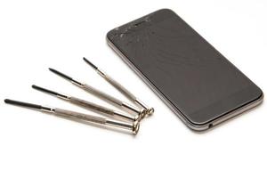 Broken smartphone and small screwdrivers for repair photo