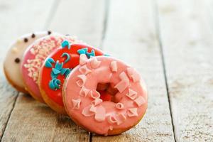 Colorful donuts on wooden table photo