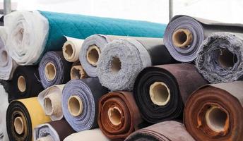 Close up view on rolled samples of cloth and fabrics in different colors found at a fabrics market.. photo