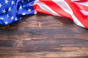 Close-up of the American flag is placed on the left side with copy space on a wooden table background photo