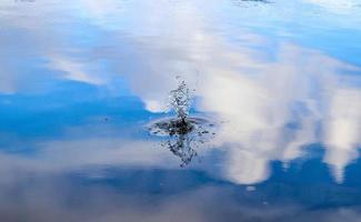 hermosa agua en un lago con agua salpicada y ondas en la superficie con nubes y reflejos de cielo azul foto