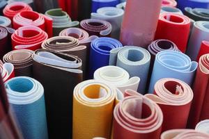Close up view on rolled samples of cloth and fabrics in different colors found at a fabrics market.. photo