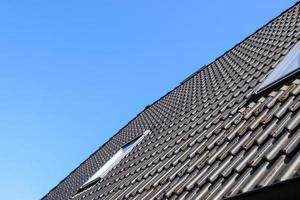 Roof window in velux style with black roof tiles. photo