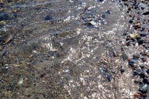 Detailed close up view on water surfaces with ripples and waves and the sunlight reflecting at the surface photo