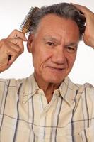 Mature man 60 plus combing his hair with a brush photo