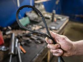 Old worn rubber alternator belt in men's hands. The concept of car maintenance. Copy space photo