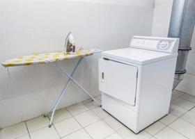 laundromat. Laundry room for clothes. Iron and washing machine photo