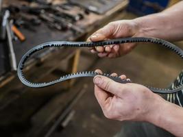 Old worn rubber alternator belt in men's hands. The concept of car maintenance. Copy space. photo