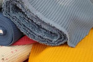 Detailed close up view on samples of cloth and fabrics in different colors found at a fabrics market photo