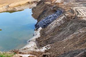 View into a gravel pit with piles of sand and some tire tracks photo