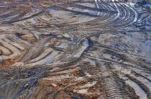 View into a gravel pit with piles of sand and some tire tracks photo