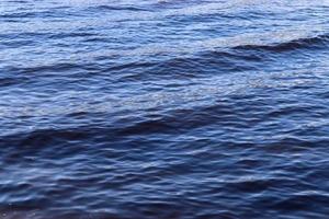 Detailed close up view on water surfaces with ripples and waves and the sunlight reflecting at the surface photo