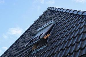 Open roof window in velux style with black roof tiles. photo