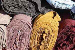 Close up view on rolled samples of cloth and fabrics in different colors found at a fabrics market.. photo