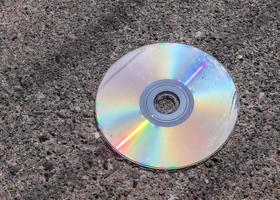 Old used compact disc on an asphalt road. Close up view. photo