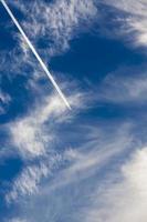 un avión volando a través de un cielo nublado azul foto