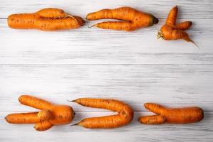 Ugly carrots lie on a light wooden surface photo