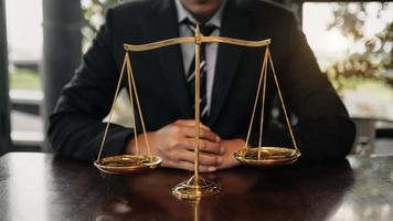 abogado masculino en la oficina con escala de latón sobre mesa de madera. concepto de justicia y derecho en la oficina foto