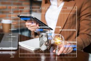 business man hand holding lightbulb with using smartphone and calculator to calculate saving energy photo