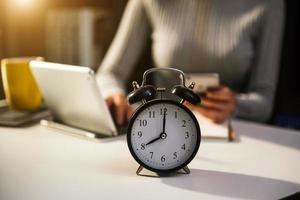 Alarm clock on the desk. Business working in modern office building or home at night using laptop. photo