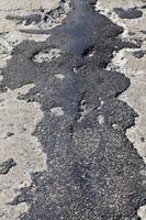 a bad asphalt road that has been repaired many times photo