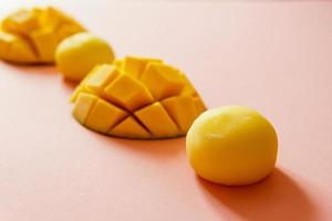 sabroso postre mochi con fruta de mango sobre fondo rosa, de cerca. foto