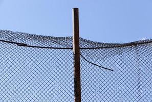 old wire fence made of thin wire against the blue sky photo