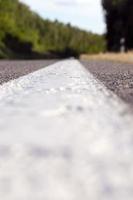 close up of an asphalt road with white road markings photo