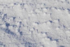 tierra cubierta de nieve blanca como la nieve después de que la nieve había caído y cubrió la tierra en el campo agrícola. primer plano de la foto en la temporada de invierno, una pequeña profundidad de campo. en la superficie visible rugosidad nieve