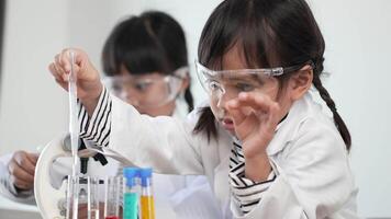 Slow motion shot, Two asian siblings wearing coat and clear glasses use microscope for experimenting with liquids, while studying science chemistry video