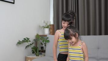 fille asiatique sœur debout et se préparant à la pose de méditation, s'entraînant sur tablette dans le salon, riant avec plaisir video