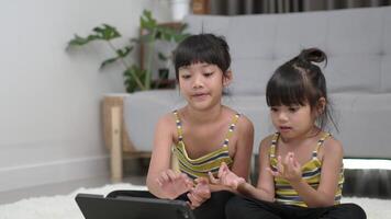 syskon asiatisk tjej som sitter och förbereder sig för meditationsställning, tränar på surfplatta i vardagsrummet, le med glad video