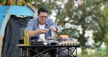 primer plano de freír un sabroso huevo frito en una sartén caliente en el camping. cocina al aire libre, viajes, camping, concepto de estilo de vida. video