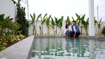 toma en cámara lenta, pareja joven asiática disfruta hablando juntos en la piscina en el nuevo hogar, concepto de familia feliz video