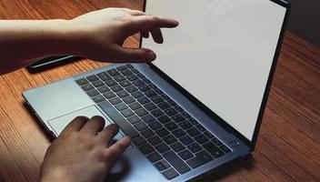 Mockup image with computer blank screen and hand pointing to screen. Background for advertising text. Woman using laptop at desk. Space for design. photo