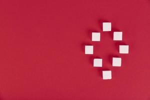 White sugar cubes on a red background in the form of the number zero.Copy space. photo