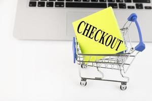 Shopping cart, laptop, text, CHECKOUT, on yellow paper. business photo