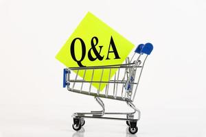 Cart and the text Q and A means questions and answers on yellow paper, business concept, over white background. Copy space. photo