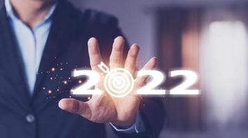 objetivo comercial y objetivo en el concepto de año nuevo 2022, mano sosteniendo la pantalla virtual 2022. negocio de año nuevo. nuevas ideas surgiendo en el futuro. foto