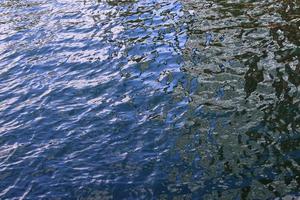 Detailed close up view on water surfaces with ripples and waves and the sunlight reflecting at the surface photo