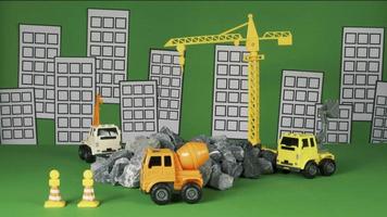 Stop-motion on green background, construction vehicles toys, trucks, backhoes, and cranes work at site, transport resource materials, rock, and mortar, real estate business, and city development. video