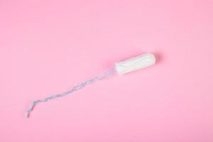 Hygienic cotton tampon on pink background. Feminine menstrual hygiene product. photo