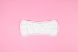Sanitary pad on pink background. Daily feminine hygiene product. Menstruation concept. photo