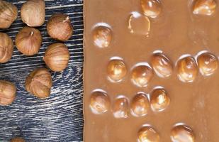 bitter real chocolate, photographed close up with whole hazelnuts inside and next to a bar of broken chocolate photo