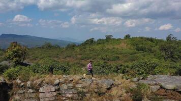 Aerial drone view, Young hiking man with backpack walking with happy on peak of rocky mountain, panning video shot