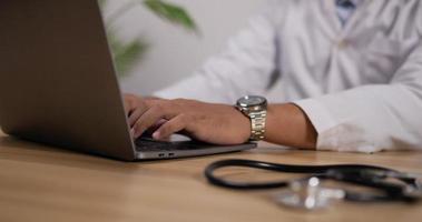 Nahaufnahme der Hand eines männlichen Arztes, der Laptop mit Stethoskop vorne tippt. medizinisches und gesundheitskonzept. video