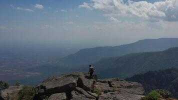 Aerial drone view, Rear view Young hiking man walking and rise-up hands with happy on peak of rocky mountain video